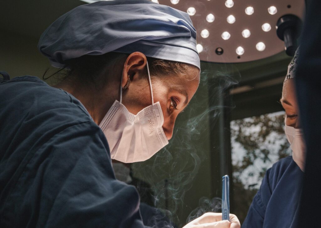 Female surgeons in SP, Brazil focusing on intricate operation under bright surgical light.